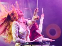 Group of female drummers in stage costumes in the circus arena in the light of spotlights and smoke